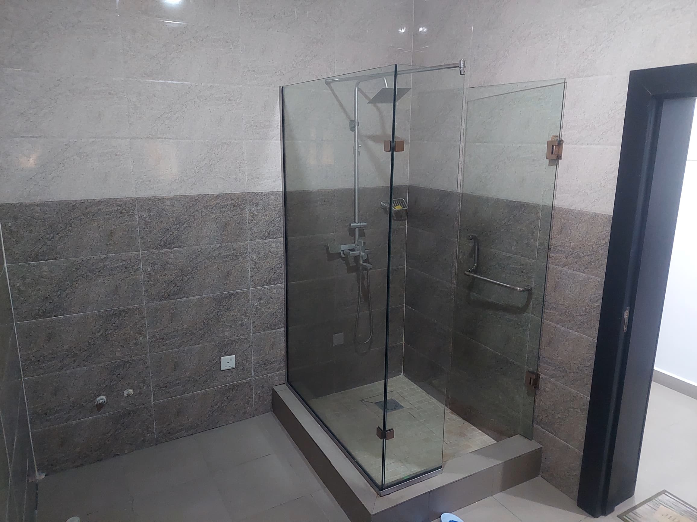 A stone-tiled bath with a frameless glass shower